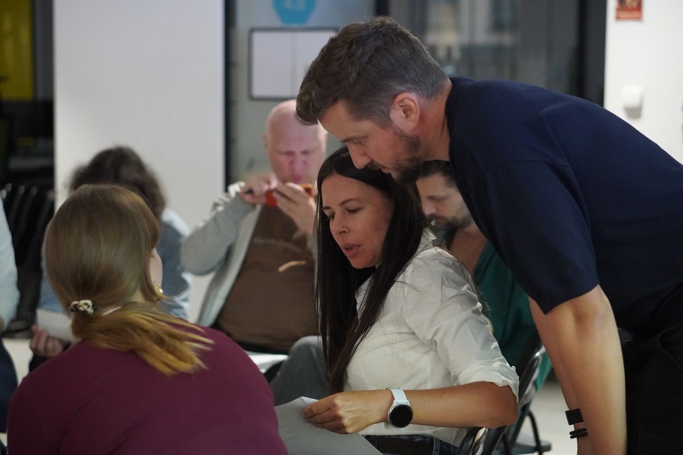 Aleksander Uznański leaning over a table to help a workshop group working through the 3W Loop at Product Peak Wrocław