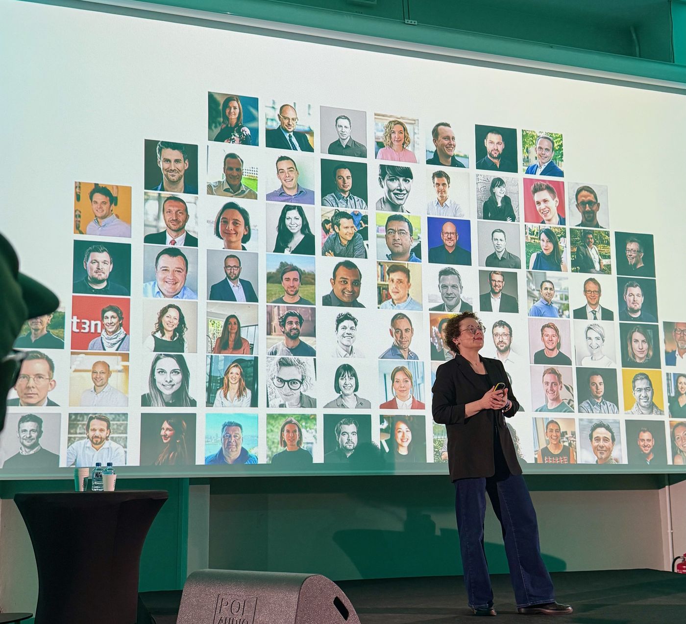 Petra Wille on stage at WaysConf 2026 in front of a wall of portrait photos of product people
