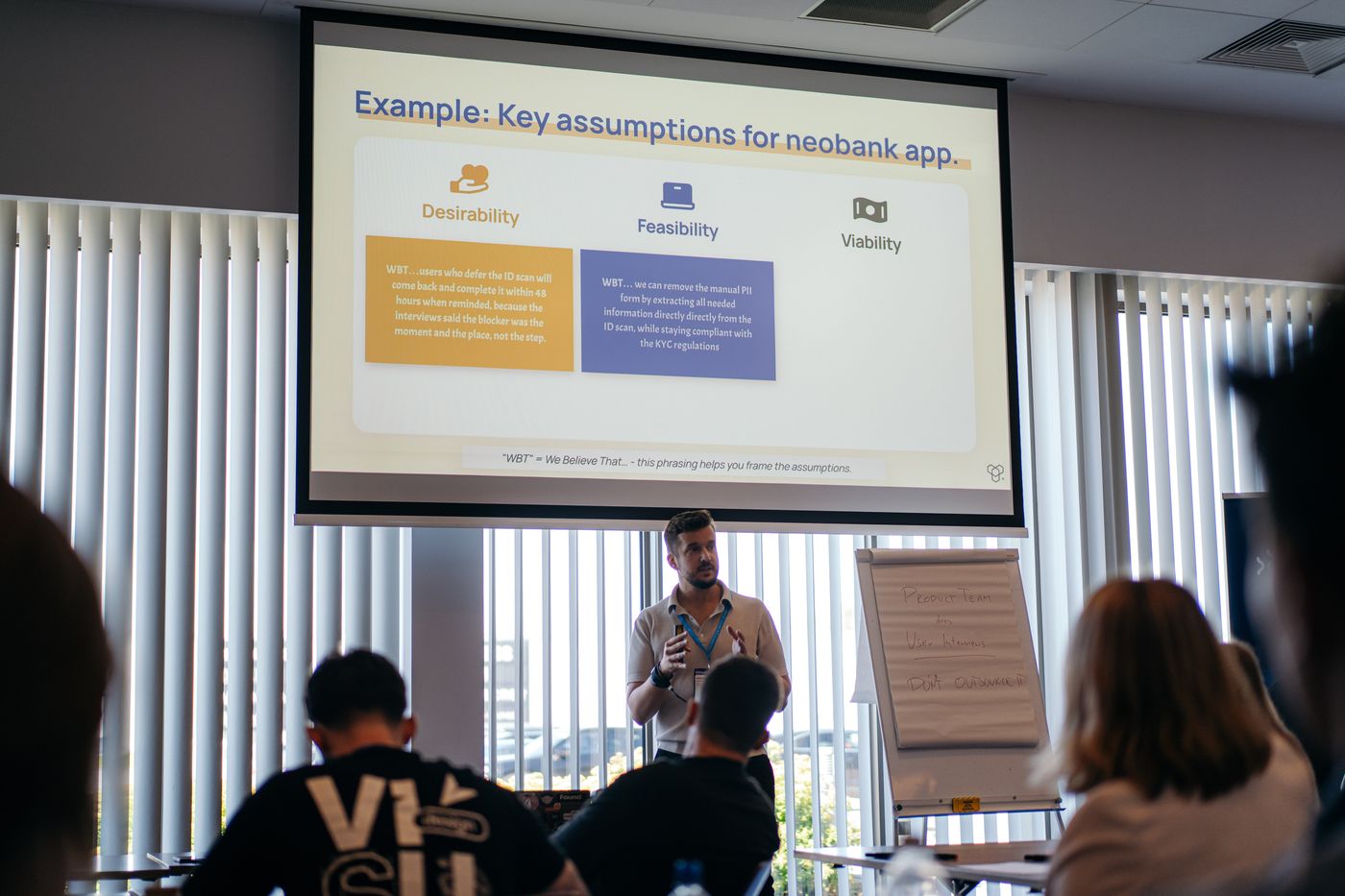 Aleksander Uznański presenting a slide titled Example: Key assumptions for neobank app, split into desirability, feasibility and viability, at the WaysConf 2026 workshop